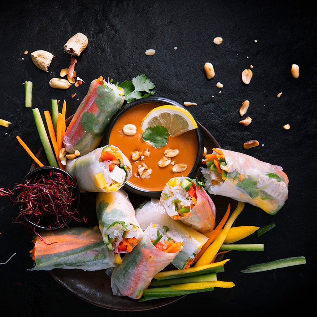 Frisch angerichtete Summer Rolls gefüllt mit knackigem Gemüse und frischen Zutaten, serviert mit aromatischem Dip auf einem Teller.